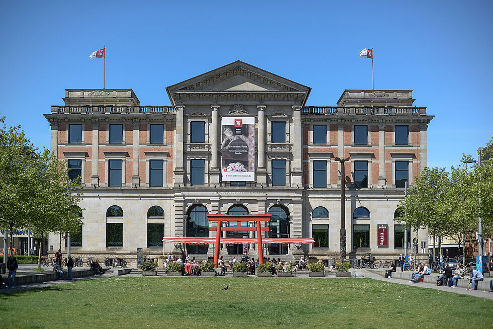 Backsteingbäude steht hinter einer Grünfläche